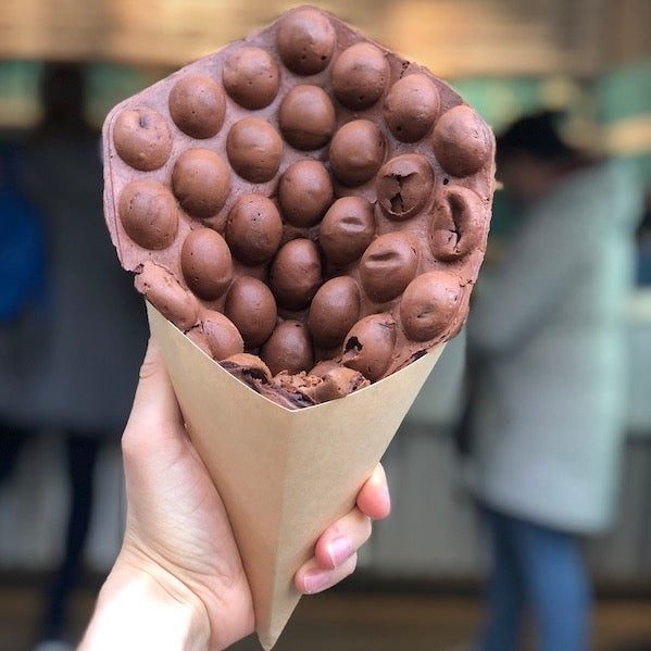 Schoko-Bubble-Waffle in der Papiertüte, in der Hand gehalten