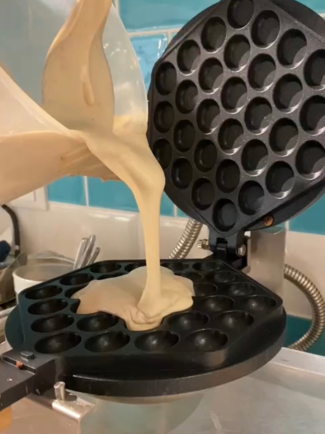 Bubble-Waffle-Teig wird in das heiße Waffeleisen gegossen