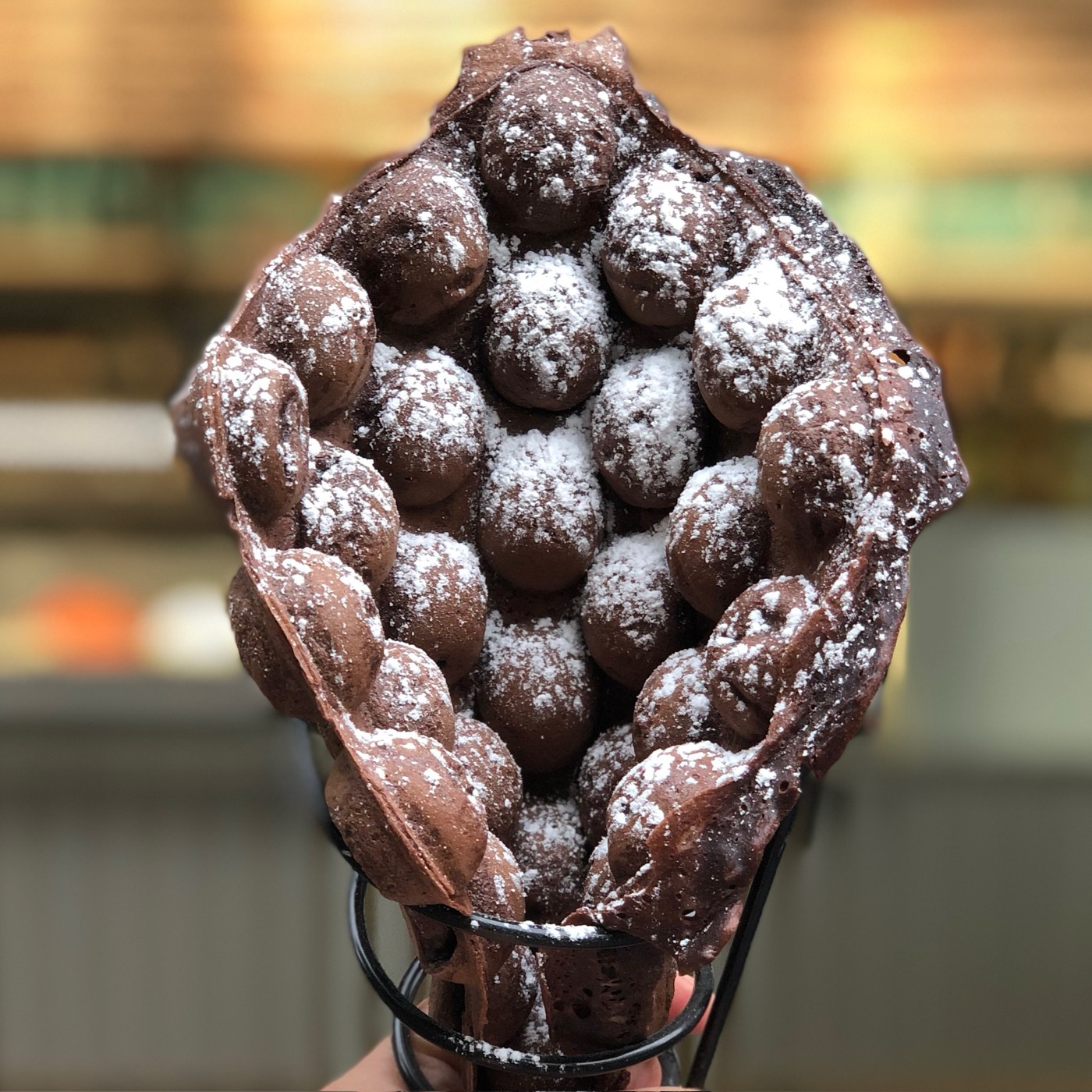 Schoko-Bubble-Waffle mit Puderzucker in der Tüte
